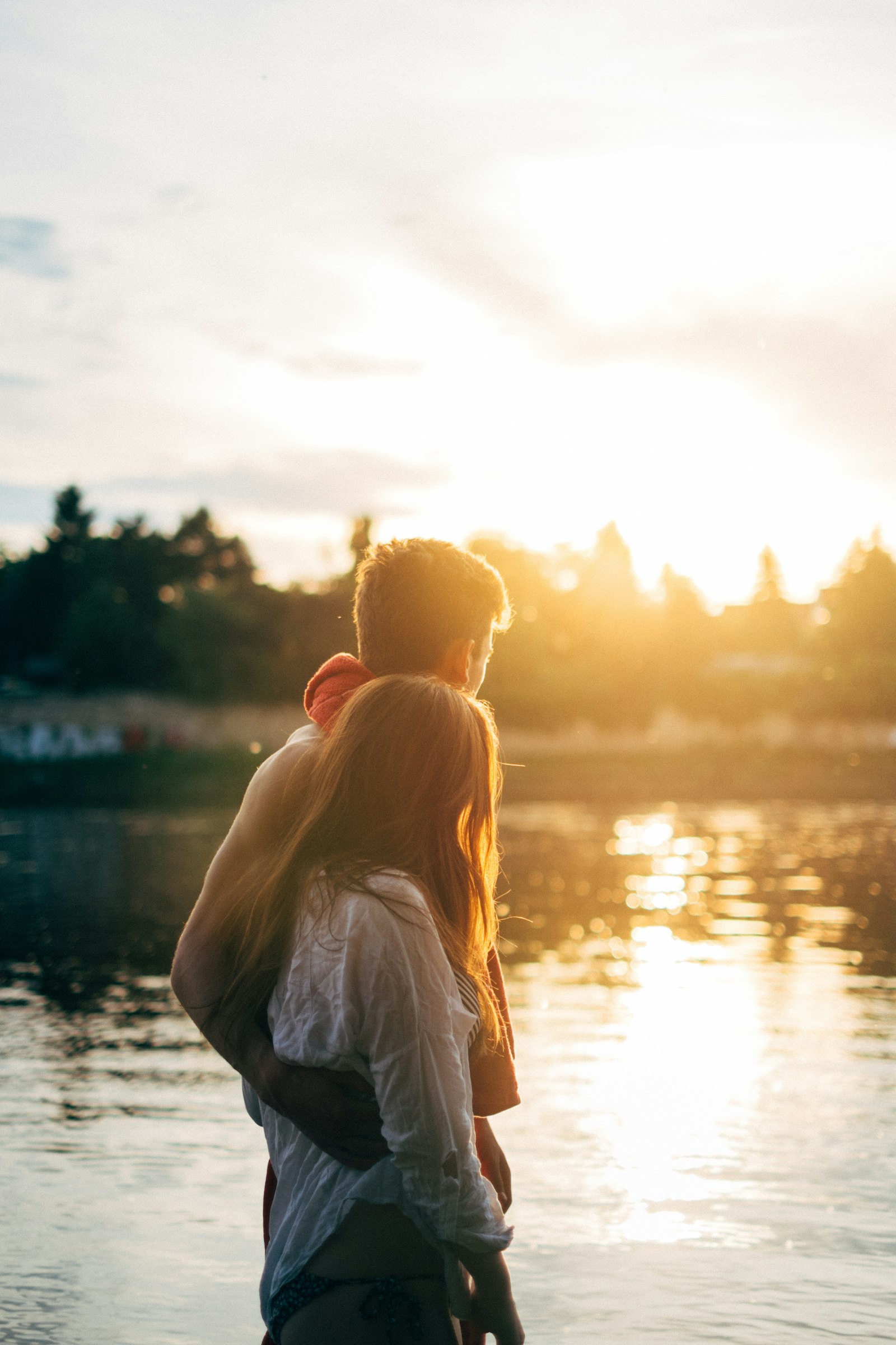 A couple standing by the water as the sun sets